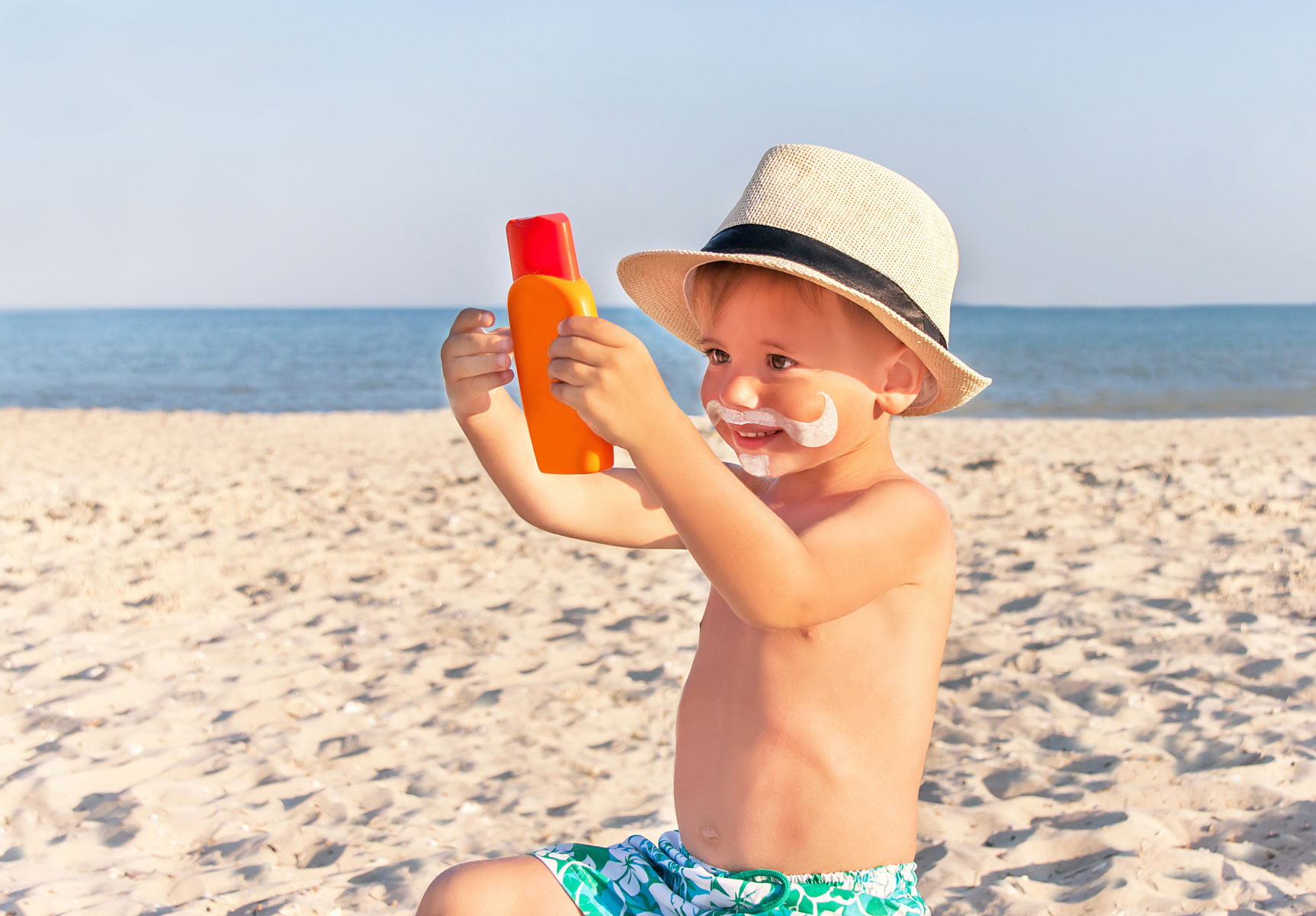 The mustache drawing sunscreen on baby (boy) face.